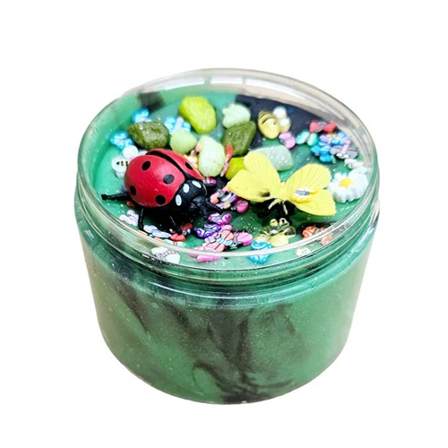 insekten speelklei2 Doosje gevuld met groene sensorische klei, versierd met lieveheersbeestje, bij, kleurrijke steentjes, bloemetjes en kleine vlinders – een vrolijke lentetuin in miniatuurformaat.