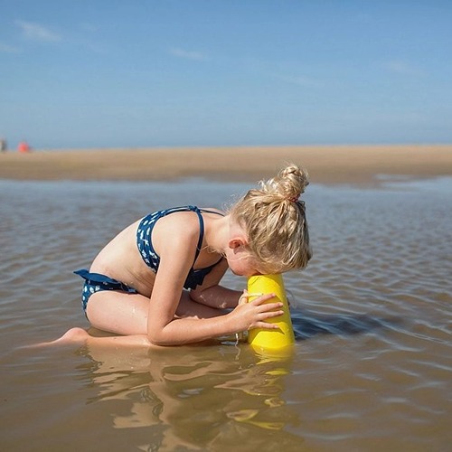 Kind gebruikt waterkijker als waterspel in ondiep water